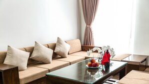 A modern living room with a beige sofa, a glass coffee table, and a small side table. - Liberty Hotel - Events (Lao Cai)