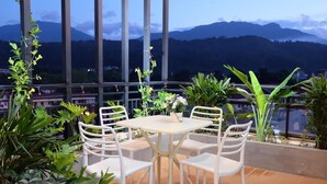 A terrace with a table and chairs, surrounded by various plants, overlooking a mountainous landscape. - Liberty Hotel - Events (Lao Cai)
