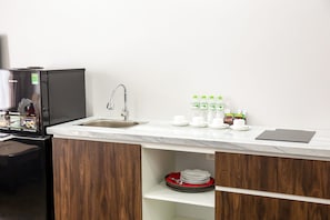 A compact kitchen with a sink, a refrigerator, and a countertop with a tablet. - Liberty Hotel - Events (Lao Cai)