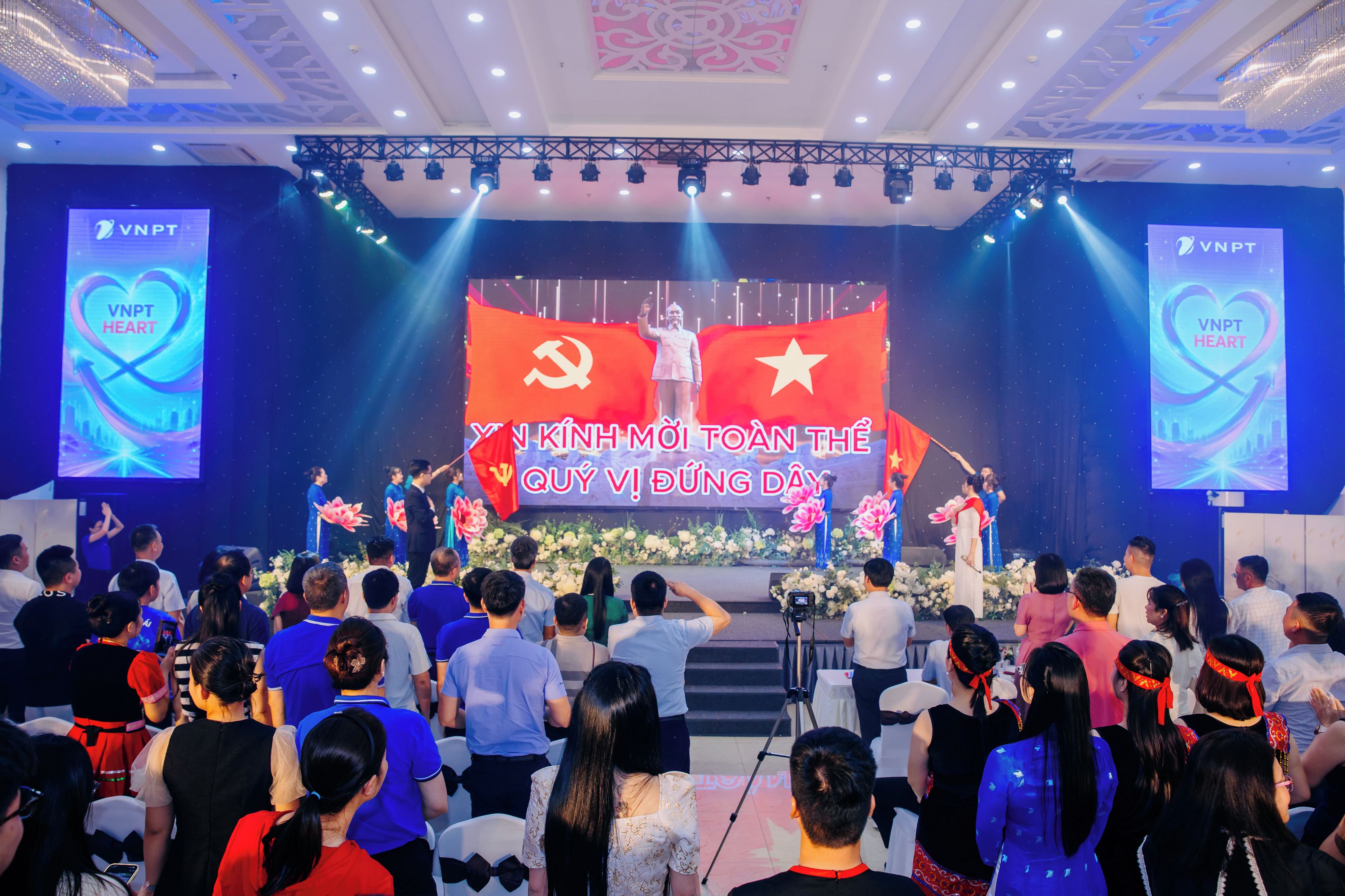 Palco com uma bandeira grande e um banner, rodeado por uma plateia.