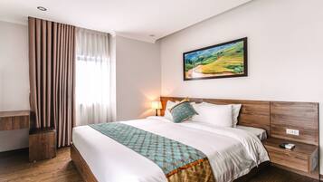 Habitación de hotel con una cama grande, una mesita de noche, una lámpara y un cuadro de un paisaje en la pared.