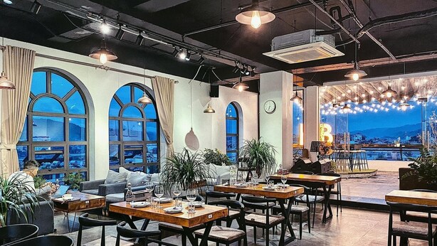 A restaurant with tables and chairs, large windows, and a view of the city. - Liberty Hotel - Events (Lao Cai)