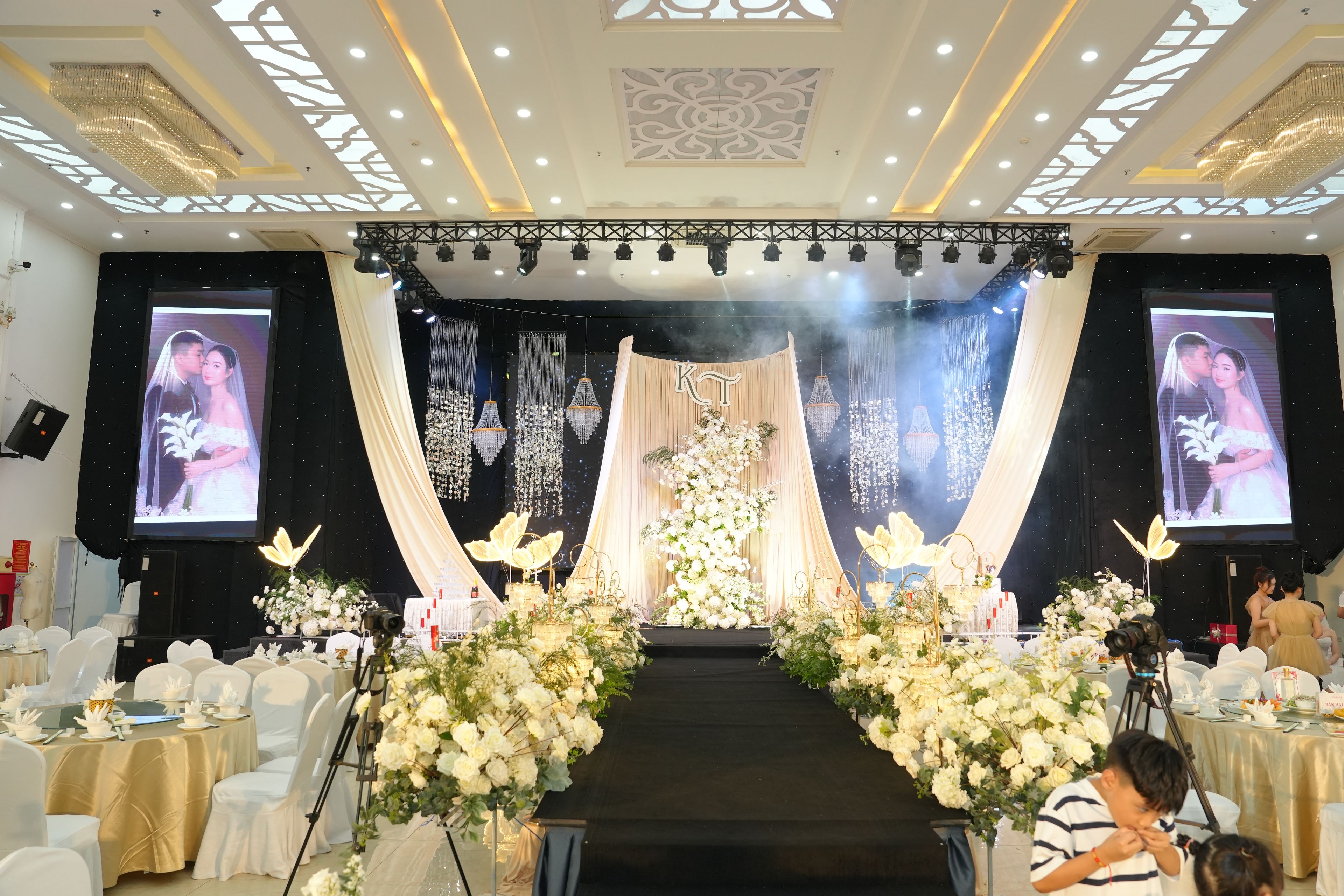 A stage with a floral arrangement, a podium, and two screens displaying images.