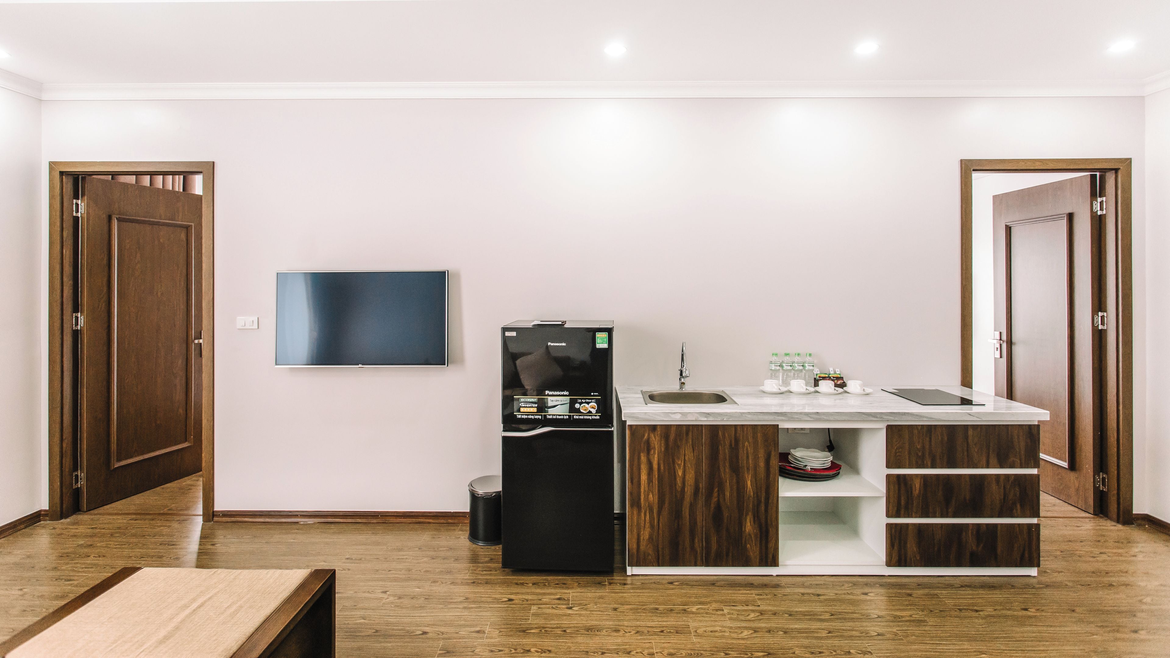 A compact kitchen with a built-in refrigerator, a flat-screen TV, and a sink.