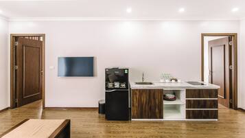 A compact kitchen with a built-in refrigerator, a flat-screen TV, and a sink.
