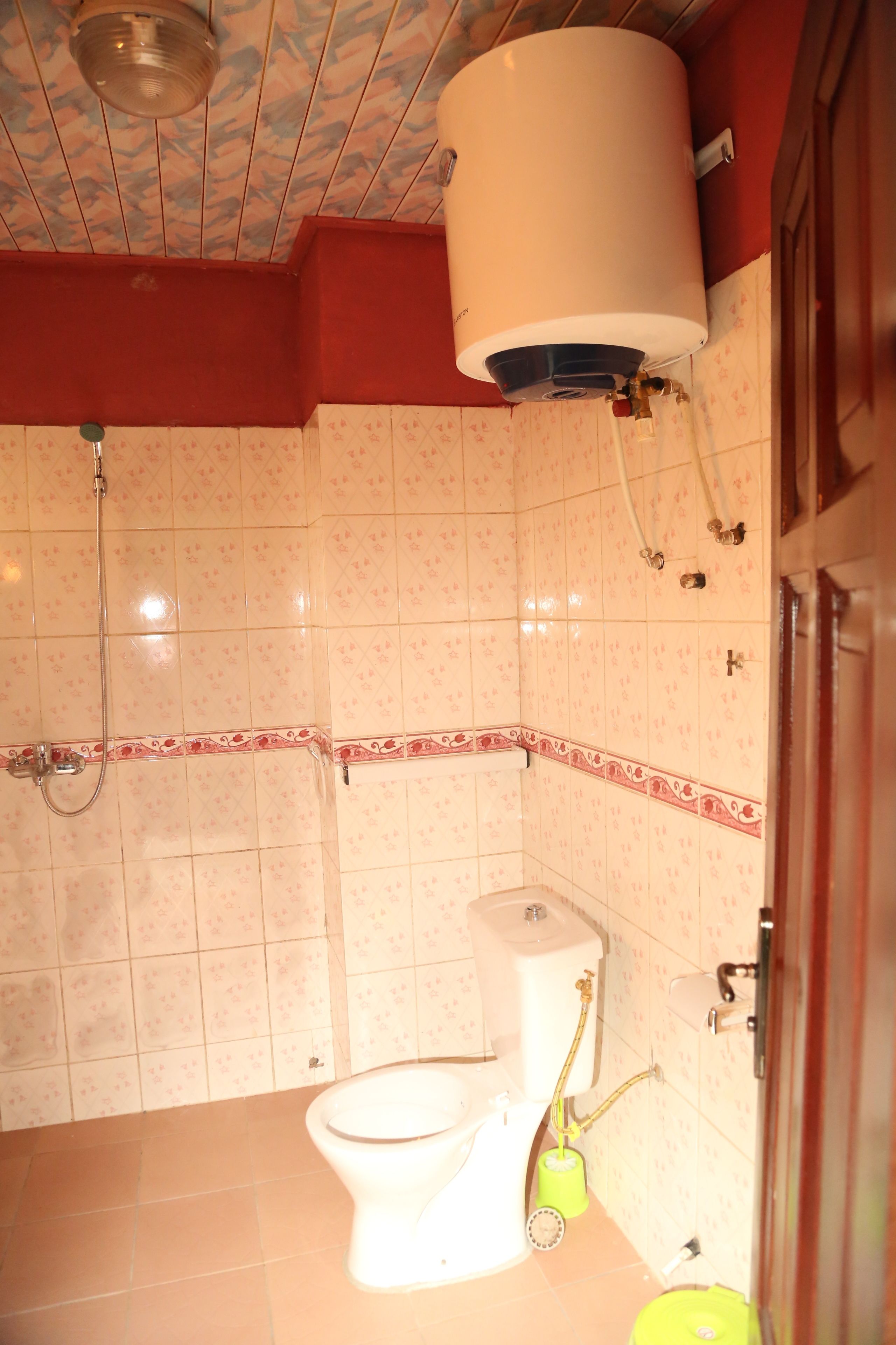 A bathroom with a toilet, a shower, and a water heater mounted on the wall.