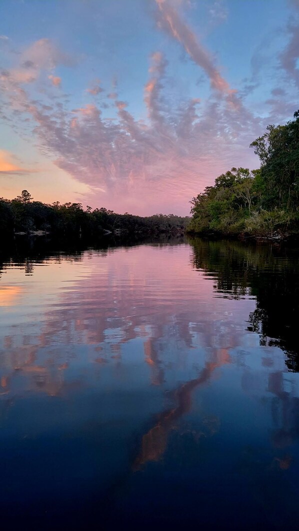 A calm river reflecting the sky with trees on both sides.