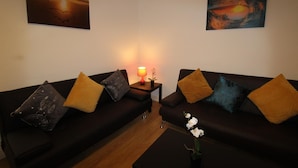 A living room with two dark sofas, a small table with a lamp, and a flower vase. - PearTree House (Derby)