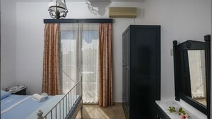 A bedroom with a bed, a wardrobe, a desk with a mirror, and a window with curtains. - Casa Kounopetra (Kefalonia)