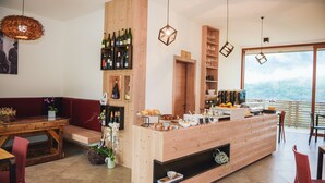 A modern kitchen with wooden accents, a bar area with wine bottles, and a view of the mountains. - Agritur Verderame (Trento)