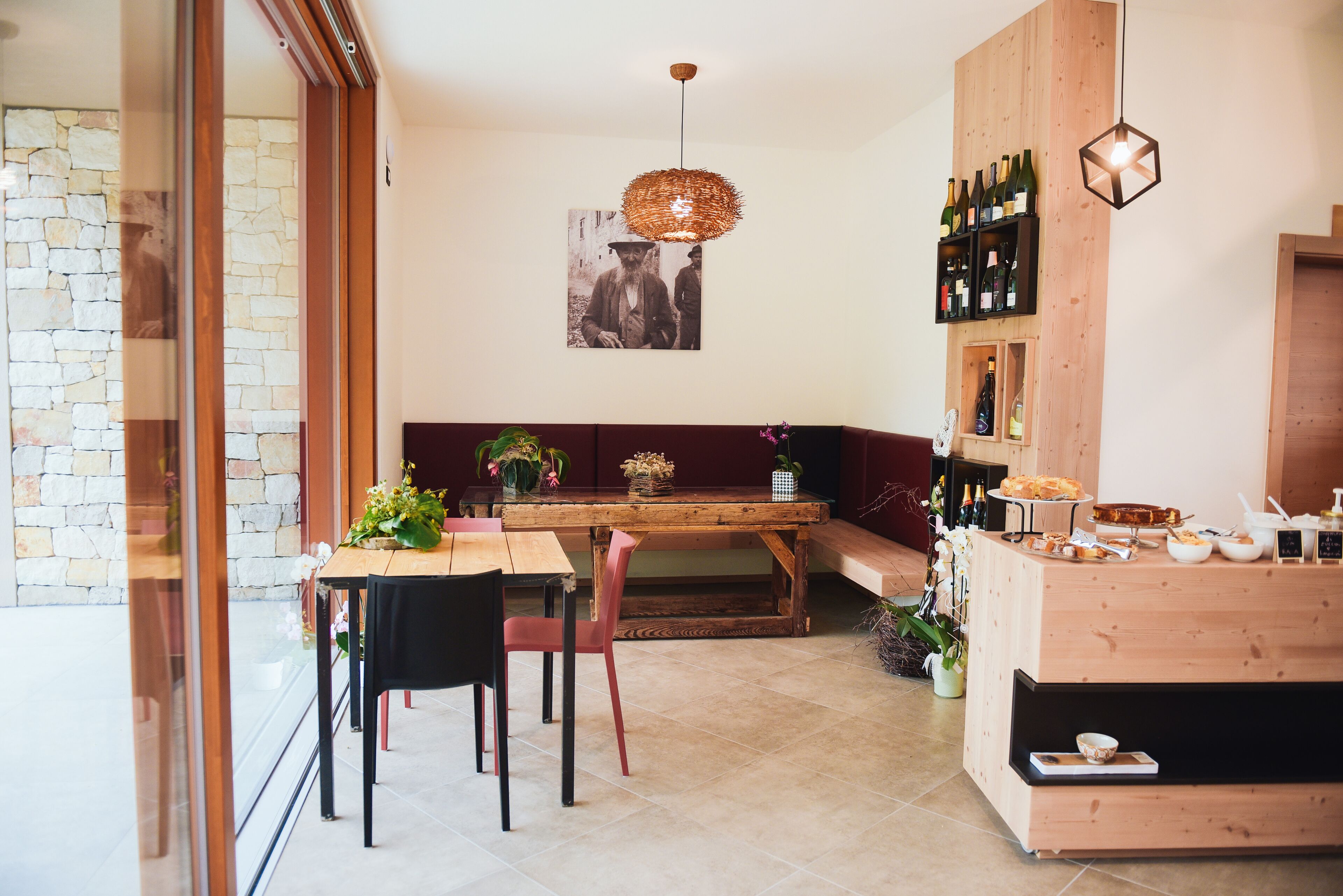 Un espace repas moderne avec une table en bois, des chaises et un banc. Un porte-bouteilles fixé au mur expose différentes bouteilles de vin.