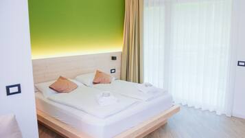 Ein modernes Hotelzimmer mit einem hölzernen Bett, einer grünen Akzentwand und transparenten Vorhängen.