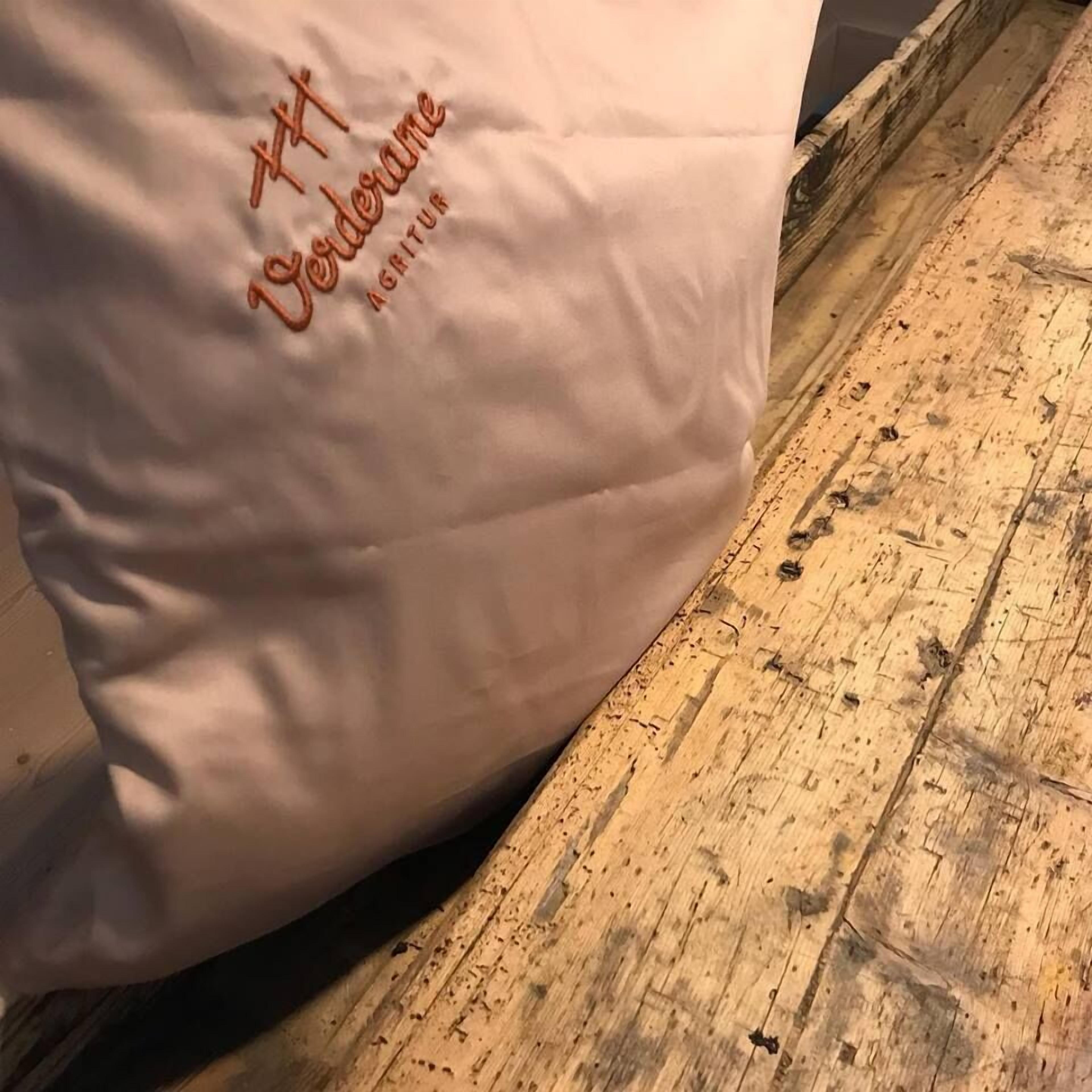A white pillow with the text "Vorderame" and "AGENTUR" on it, placed on a wooden floor.