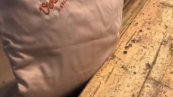 A white pillow with the text "Vorderame" and "AGENTUR" on it, placed on a wooden floor.