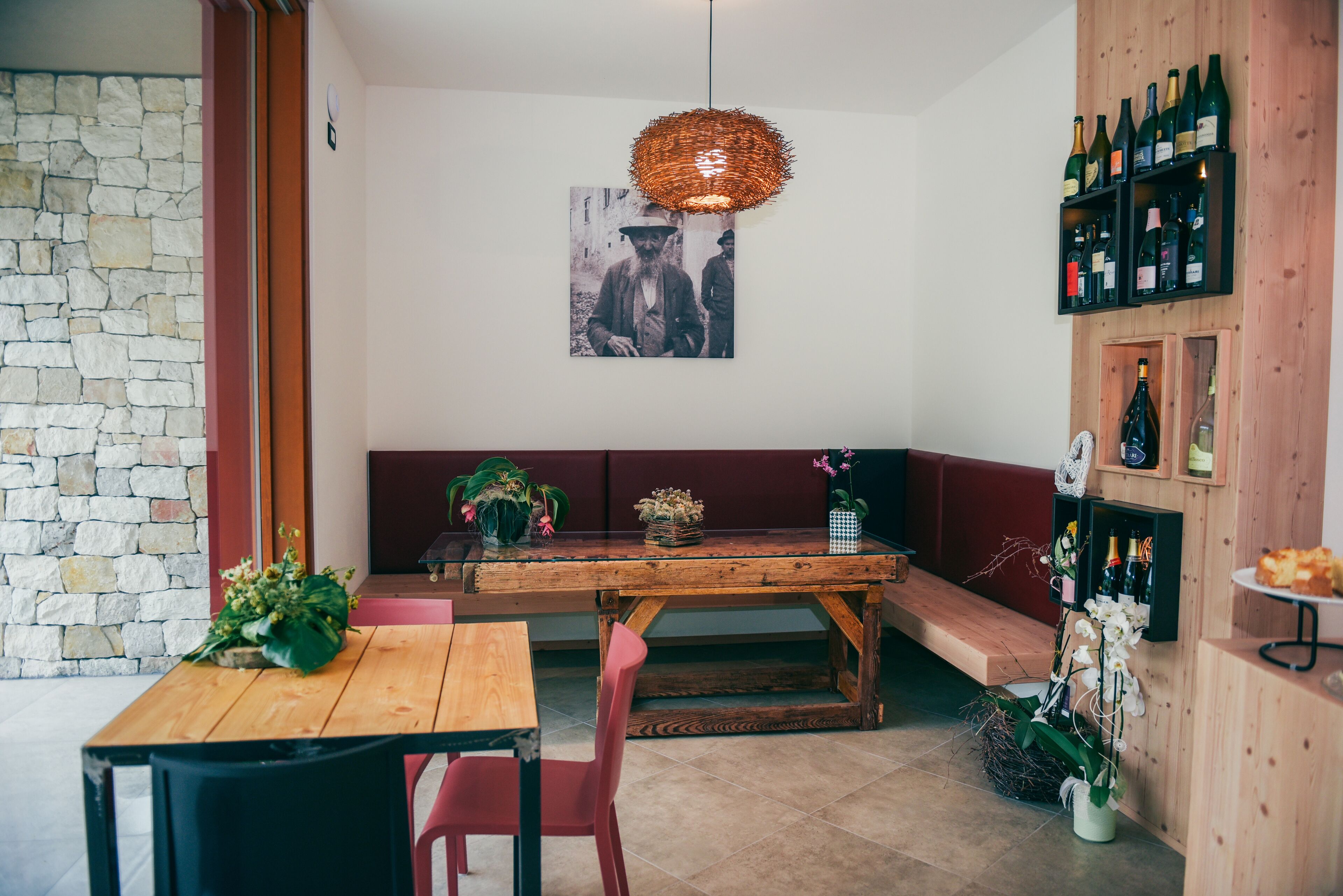 Un comedor acogedor con una mesa y sillas de madera, una pared de piedra, una lámpara colgante y una estantería para vinos.