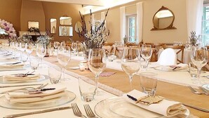 A banquet hall with long tables set for a formal event, featuring clear glassware, folded napkins, and elegant table settings.