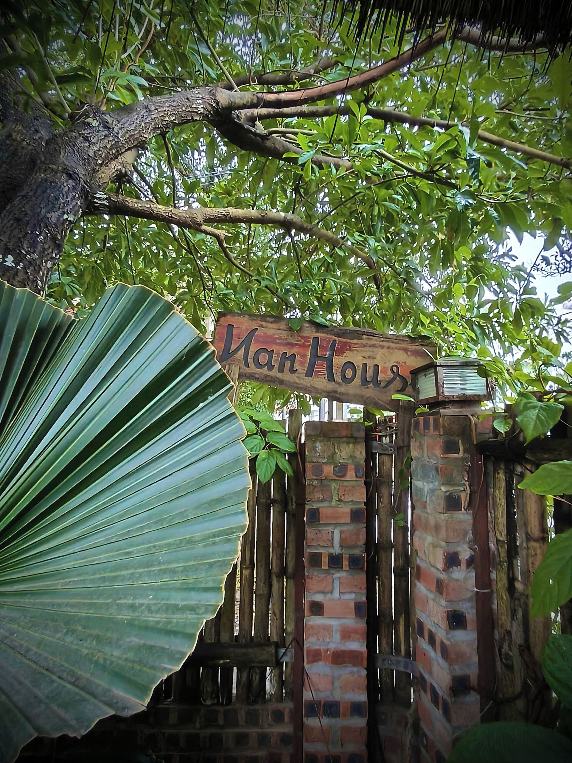 A wooden sign with the text "Van House" hanging above a brick gate.