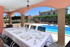 Un comedor con mesas dispuestas para una comida, con vistas a una piscina.