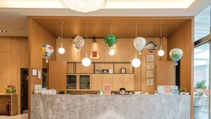 A hotel reception desk with a marble counter, hanging decorative lights, and a wooden interior.