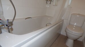 A bathroom with a bathtub, toilet, and a showerhead. - Boythorpe House (Chesterfield)