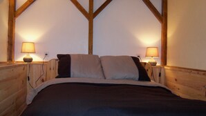 A wooden-framed room with a bed, two bedside lamps, and a simple wall design. - Chambre D'hote et Gite Le Parc (Revel)
