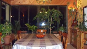 A dining area with a checkered tablecloth, wooden chairs, a chandelier, and potted plants. - Chambre D'hote et Gite Le Parc (Revel)