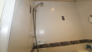 A bathroom with white tiles, a glass shower enclosure, and a tiled border. - Depedale House (Derby)