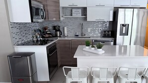 Una cucina moderna con elettrodomestici in acciaio inossidabile, un'isola centrale con sgabelli da bar e un pannello decorativo.