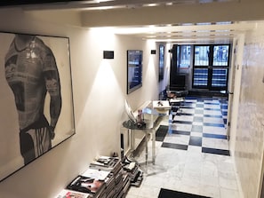 A hallway with a checkered floor, a glass display case with magazines, and framed pictures on the walls. - Downtown Room In Canal District (Amsterdam)