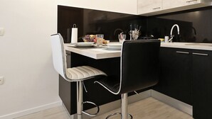 Una cocina moderna con comedor, con una paleta de colores blanco y negro, electrodomésticos de acero inoxidable y un diseño minimalista.