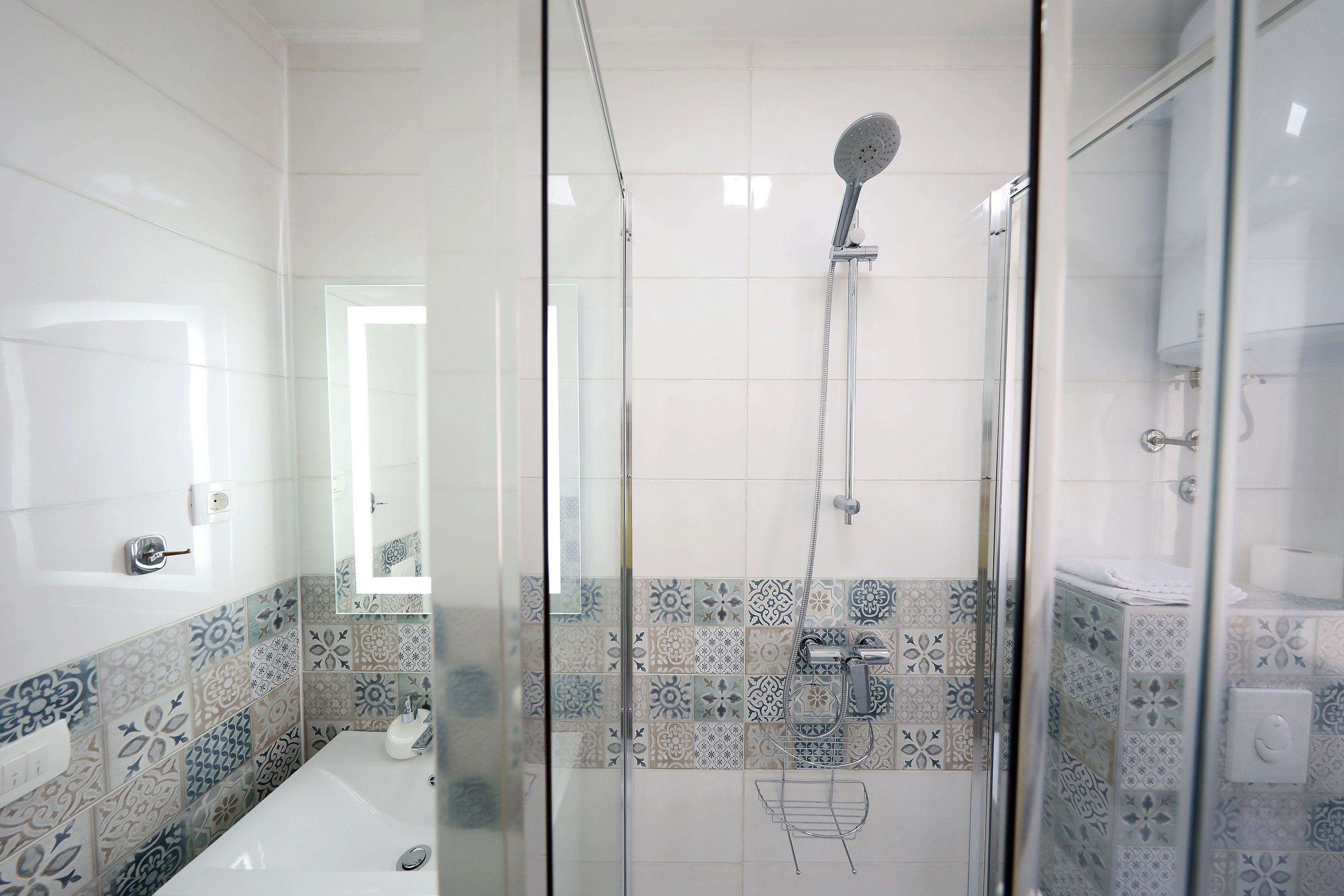 Un baño moderno con ducha de vidrio, bañera blanca y azulejos con diseño.
