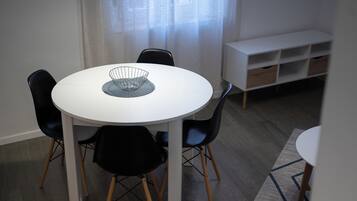 A dining area with a round white table, black chairs, and a white cabinet with drawers.