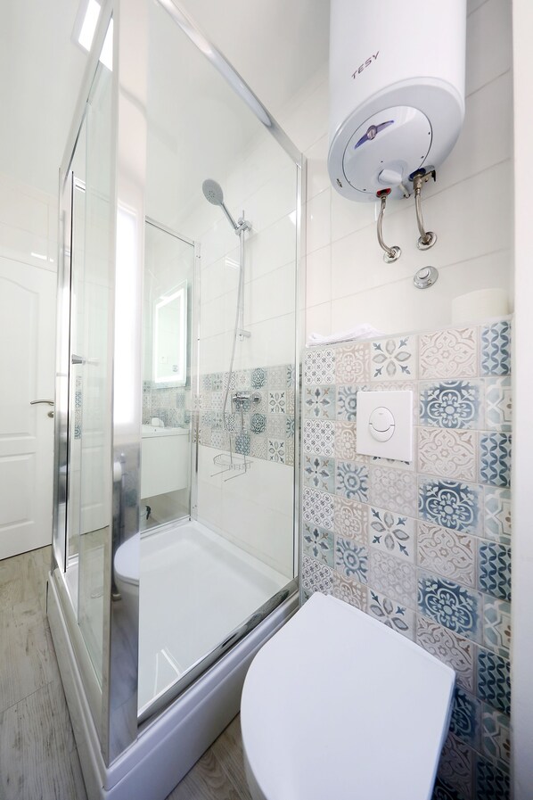 Un baño moderno con ducha de vidrio, inodoro blanco y azulejos estampados en las paredes.
