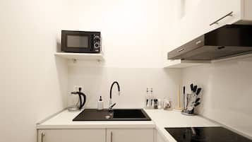 A compact kitchen with a microwave, sink, and stove.