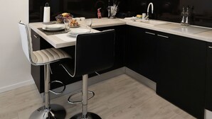 Una cocina moderna con encimera negra, armarios blancos y un taburete de bar.