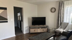 Een woonkamer met een flatscreen televisie, een salontafel, een bank en een kamerbreed tapijt met dessin.