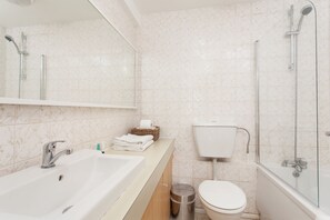 A modern bathroom with a large sink, a toilet, and a glass-enclosed shower area.