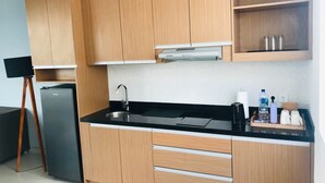A modern kitchen with wooden cabinets, a black countertop, a stainless steel sink, and a compact refrigerator. - Villa Ommy Hideway Residence No.108 (Ungasan)