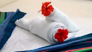A neatly made bed with white linens and two red hibiscus flowers placed on the pillows. - Wildshade safari Lodge Udawalawa (Udawalawa)