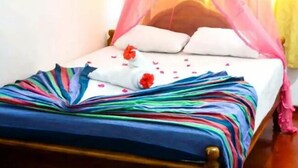 A bed with a colorful striped bedspread, white pillows, and a pink canopy. - Wildshade safari Lodge Udawalawa (Udawalawa)