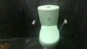 A toilet with a white tank and seat, set against a dark background with a stone floor. - Wildshade safari Lodge Udawalawa (Udawalawa)