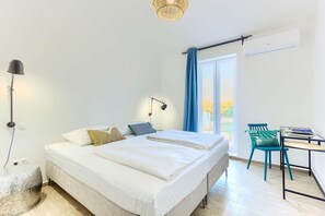 Une chambre à coucher avec un lit, des lampes de chevet, un bureau avec une chaise et une fenêtre avec des rideaux.