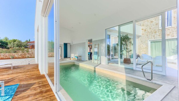 Een modern huis met een zwembad, grote glasramen en een stenen gevel.