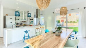 Een moderne keuken met witte kastjes, een houten kookeiland en blauwe barstoelen.