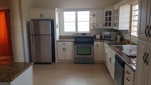 Una cocina con armarios blancos, un refrigerador, un horno, un microondas y un lavaplatos.