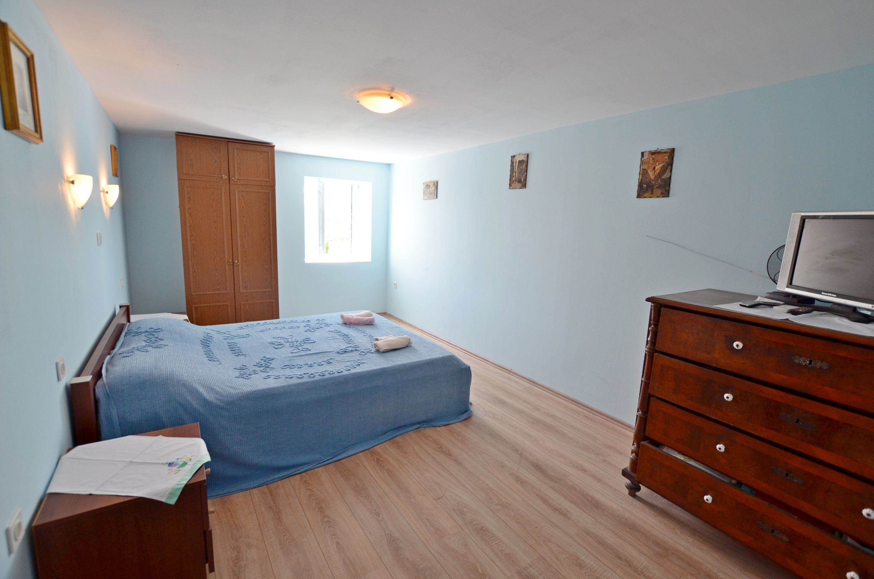 Une chambre à coucher comprenant un lit, une commode en bois, une armoire et un téléviseur.