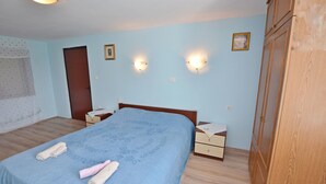 Un dormitorio con una cama, dos mesitas de noche, un armario y dos luces fijadas a la pared.