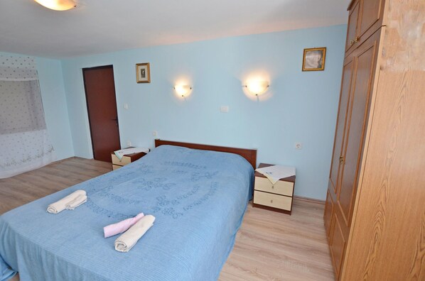 Quarto com cama, duas mesas de cabeceira, um guarda-roupa e duas luzes na parede.