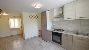 Una cocina moderna con armarios de madera clara, una estufa a gas y un horno empotrado.