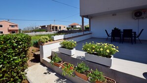 A modern residential building with a flat roof terrace, outdoor seating area, and potted plants. - Apartment Maja (Vrsi)